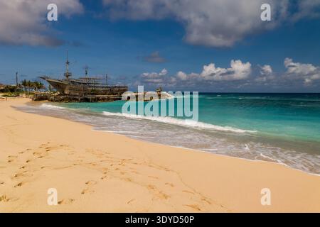 Tropischer Sandstrand mit sanften Wellen und einer großen Holzstruktur auf Felsen Stockfoto