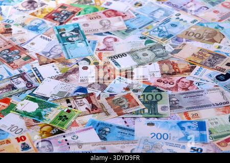 Viele Banknoten unterschiedlicher Währung. Eine große Menge von zufälligen Geldrechnungen aus der Nähe. Währungsumtausch-Konzept Stockfoto