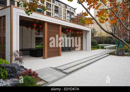 Detaillierter Blick auf einen eleganten Gemeindepavillon mit Holzschiebetüren, Stufen und roten Laternen in einem gepflasterten wohnplatz. Das Bild wird übertragen Stockfoto