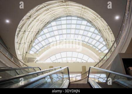 Helles Gewölbedach im geräumigen Atrium mit Rolltreppen und Reling, Lobbykonzept des Firmensitzes und Schaufenster für Gewerbeobjekte Stockfoto