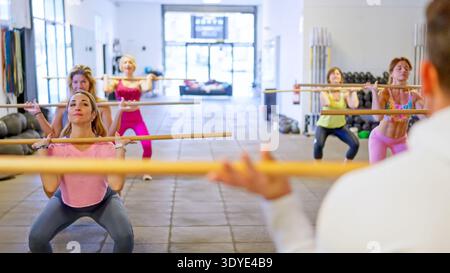 Frauen-Gruppentraining mit Fitnessstöcken in den vorderen Hocken Stockfoto