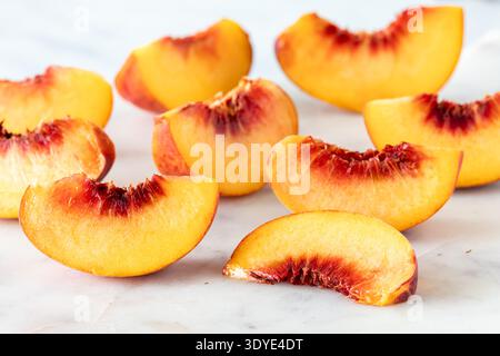 Reife und saftige freie Steinpfirsichsegmente vor hellem Hintergrund. Stockfoto