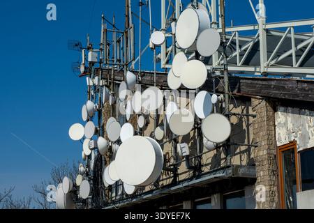 Satelliten-Kommunikationsschalen und TV-Radiosender an der Gebäudewand Stockfoto