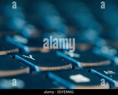 Blau getönte Tastatur Nahaufnahme mit geringer Schärfentiefe. Die Tasten scheinen abgenutzt zu sein, was auf den täglichen Gebrauch hinweist. Der Fokus liegt auf den zentralen Tasten, leicht verschwommenes Surro Stockfoto