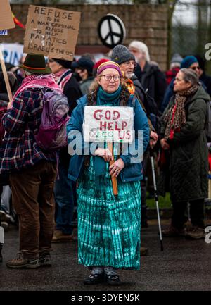 RAF Fairford, Gloucestershire, 7. März 2026. Eine Dame hält ein Plakat hoch, während sie an einem Antikriegsprotest vor einem Eingang der RAF Fairford teilnimmt Stockfoto