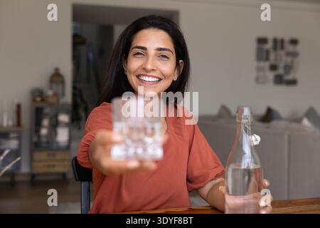 Frau, die ein Glas Wasser mit einem Lächeln anbietet Stockfoto