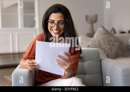 Schöne brasilianische Frau lächelt, während sie einen Brief mit guten Nachrichten liest Stockfoto