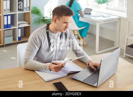 Ernsthafter Arzt auf Laptop-Bildschirm eingeklemmt, die dem Patienten verordneten Medikamente überprüfen Stockfoto