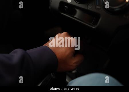 Filmaufnahme eines Fahrers, der während einer Nachtfahrt den Gang wechselt. Nahaufnahme der Hand und des Schaltkastens, die das Tastgefühl des Fahrens unterstreicht. Stockfoto