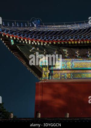 Eine dramatische Aufnahme der verzierten Dachkonstruktion eines chinesischen Tempels, die von einem warmen, goldenen Licht beleuchtet wird und komplizierte Muster und Traditiona einfängt Stockfoto