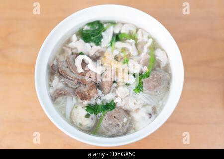 Vietnamesische Pho-Nudelsuppe mit Rindfleisch und Kräutern in weißer Schüssel auf Holztisch, Hanoi Vietnam Stockfoto