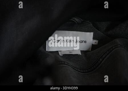 Ventspils, Lettland - 5. März 2026: Nahaufnahme eines Bekleidungsetiketts von Calvin Klein Jeans in einer schwarzen Jacke. Detailansicht des Markenkennzeichens, S. Stockfoto