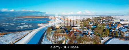 Blick aus der Vogelperspektive auf das schneebedeckte historische Dorf am gefrorenen See im Winter Stockfoto