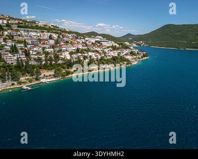Abgewinkeltes Drohnenfoto von unten, das die Adria auf der rechten Seite der Küste von Neum zeigt, Boote entlang der Küste, Wohngebäude auf den Bergen Stockfoto