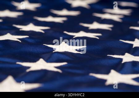 Nahaufnahme der weißen gestickten Sterne auf dem blauen Feld der amerikanischen Flagge – geringe Schärfentiefe sorgt für ein weiches, abstraktes Gefühl, das die Highlights hervorhebt Stockfoto