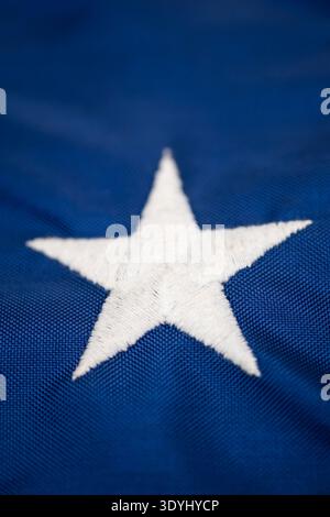 Detaillierte Makroaufnahme eines einzelnen gestickten weißen Sterns auf dem blauen Feld der amerikanischen Flagge – lebendige Textur und Nähte unterstreichen die Handwerkskunst Stockfoto