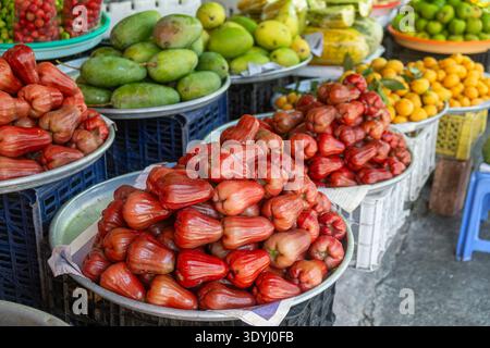 Frische tropische Früchte zum Verkauf auf dem traditionellen Lebensmittelmarkt in Phu Quoc, Vietnam. Rosenäpfel, Mangos und Loquats werden auf dem vietnamesischen Straßenmarkt ausgestellt Stockfoto