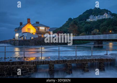 Rock House und Lynmouth Footbridge zur blauen Stunde mit Gezeitenwasser, das durch Hafenschleuse fließt, Lynmouth, Exmoor National Park, Devon, England, UK. Stockfoto