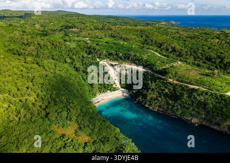 Aus der Vogelperspektive auf eine versteckte tropische Bucht mit klarem blauem Wasser, weißem Sand und dichtem Wald Stockfoto