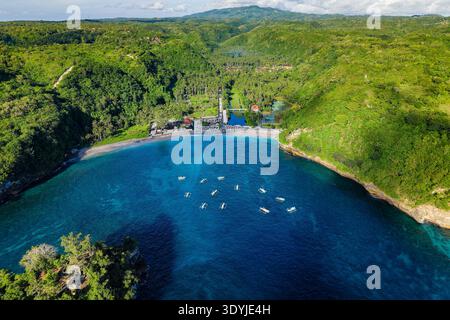 Drohnenblick auf eine tropische Inselbucht mit Booten, Sandstrand und grünen bewaldeten Hügeln Stockfoto