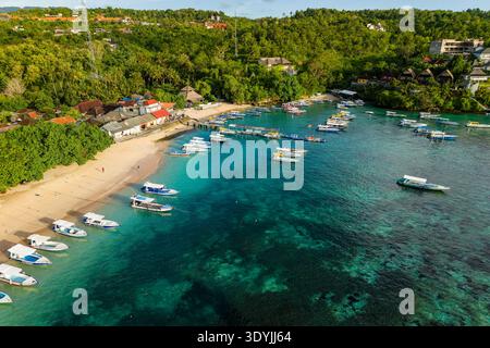 Blick aus der Vogelperspektive auf die Touristenboote, die in klarem türkisfarbenem Wasser bei Toyapakeh, Nusa Penida, verankert sind Stockfoto