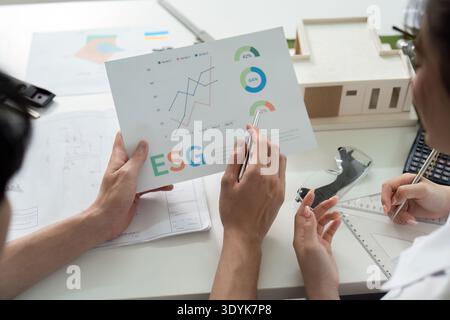 Zwei Leute sehen sich eine Zeitung mit den Buchstaben ESG an Stockfoto