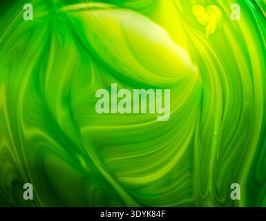 Ein abstrakter Hintergrund mit leuchtenden grünen und gelben Wirbeln, die allgemein als flüssige Marmorierung oder flüssige Maltextur beschrieben werden Stockfoto