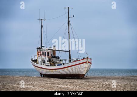 Zwei Fischerboote aus Holz am Strand ruhen an einem Kieselstrand unter einem bewölkten Himmel und vermitteln eine ruhige Küstenatmosphäre, verwitterte Texturen und nautica Stockfoto