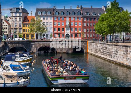 Kanalrundfahrt mit Touristen, die an der historischen Brücke und den farbenfrohen Häusern entlang des Frederiksholms-Kanals, Kopenhagen, Dänemark, vorbeifahren Stockfoto