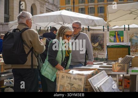 Marché à la Brocante et aux Livres. Ältere Touristen stöbern auf dem Buchmarkt in Nizza, Frankreich, auf alten Plakaten und alten Zeitungen. Stockfoto