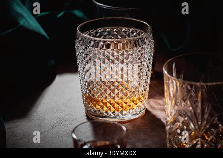 Whiskey-Glas auf Holztisch mit dramatischem Licht Stockfoto