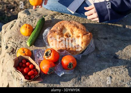 Auswahl an frischem Obst und Gemüse einschließlich Fladenbrot auf felsigem Boden für Picknicks im Freien. Stockfoto