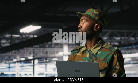 Spezialist für Informationstechnologie der Armee für die Fehlersuche in Rechenzentren bei militärischen Computersystemen und Netzwerken mit Laptops. Soldat im Serverraum der Kommandozentrale mit Notebook Stockfoto