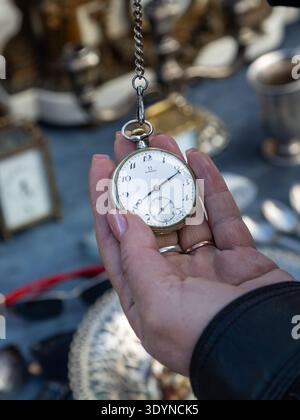 Hand hält eine Vintage Taschenuhr, während Sie auf dem Flohmarkt in Polen, dem Flohmarkt in Osteuropa, antike Artikel stöbern. Stockfoto