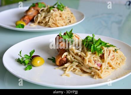 Spaghetti Carbonara, Huhn und Oliven auf einem weißen Teller Stockfoto