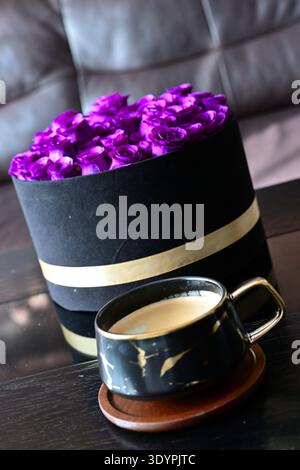 Eine Tasse Kaffee in einer Tasse mit Marmormuster und blauen Rosen im Hintergrund Stockfoto