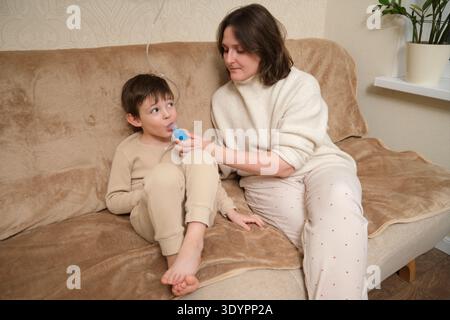 Frau, die dem Kind mit einem Inhalator und Vernebler hilft, Behandlung von Asthma. Inhalation bei Grippe, Husten und Lungenentzündung. Das ärztliche Vorgehen bei Bronchodilato Stockfoto