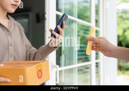 Asiatische Frau scannt QR-Code für Warenlieferung. Liefermann schickt Lieferexpress. Online-Shop, Papierbehälter, zum Mitnehmen, Postbote, Lieferservice, Stockfoto