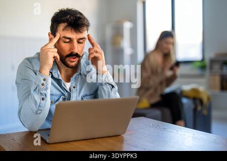 Ein fokussierter Mann arbeitet von zu Hause aus auf seinem Laptop, verwaltet Remote-Aufgaben und löst Probleme Stockfoto