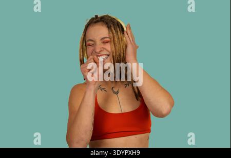Eine junge Frau mit Dreadlocks lächelt und singt zur Musik Stockfoto