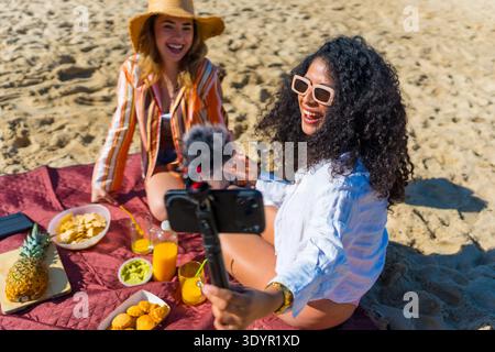 Verschiedene Freunde erstellen beim Picknick am Strand Inhalte in sozialen Medien Stockfoto