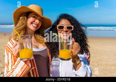 Glückliche Freunde, die den Sommerurlaub genießen und Saft am Strand trinken Stockfoto