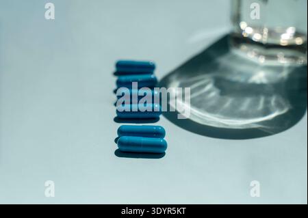 Blaue und hellblaue pharmazeutische Kapseln auf einem farblich passenden Hintergrund. Das Konzept der Laborforschung, medizinischen Behandlung und der modernen Droge Stockfoto