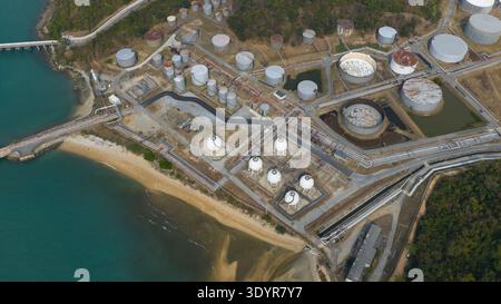 Aus der Vogelperspektive auf eine weitläufige Industrielandschaft, in der metallische Tanks unter der Sonne vor dem Hintergrund des Meeres leuchten, Thung Sukhla, Chon Buri, Tha Stockfoto