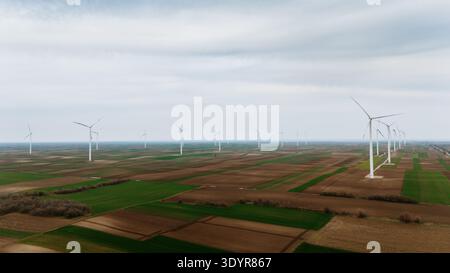 Aus der Vogelperspektive stehen Windturbinen inmitten der Flickenteppiche, ein Zeugnis für nachhaltige Energie, Alibunar, Vojvodina, Serbien. Stockfoto