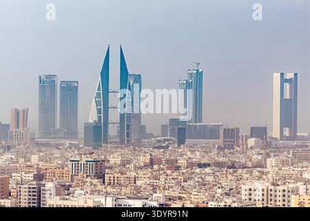 Blick auf moderne Wolkenkratzer durchdringen den trüben Himmel über einer dichten städtischen Landschaft und schaffen einen beeindruckenden Kontrast zwischen alter und neuer Architektur, Manama, B. Stockfoto
