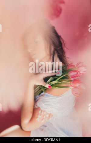 Frau, die Tulpenblumen mit rosafarbenem Hintergrund hält Stockfoto