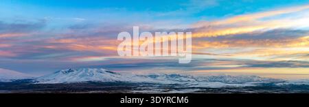 Banner mit Kopierbereich. Panoramablick auf die Berglandschaft von Aragats bei Sonnenuntergang mit einer kleinen Stadt im Tal Stockfoto