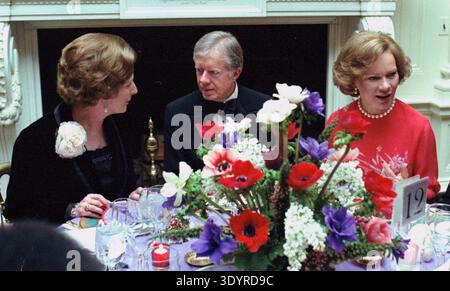 Foto mit Präsidentin Carter und Premierministerin Margaret Thatcher aus Großbritannien, die während des Dinners im Weißen Haus zu Ehren 1979 an einem eleganten, formellen Esstisch mit einem großen Blumenaufsatz versammelt wurden. 1979. Stockfoto