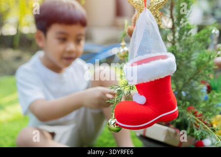Niedliches Kind, Junge, spielt im dekorierten Bereich zu Weihnachten, dekoriert weihnachtsbaum zu Hause. Selektiver Fokus, Kopierraum. Stockfoto